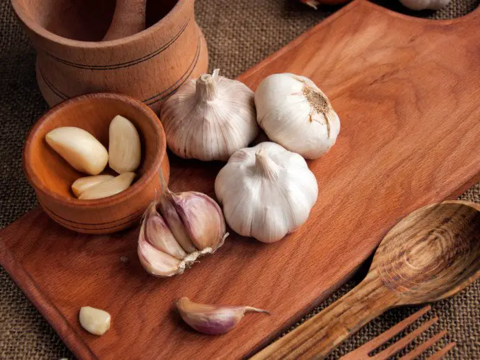 Garlic benefits - garlic and garlic cloves on wooden cutlery